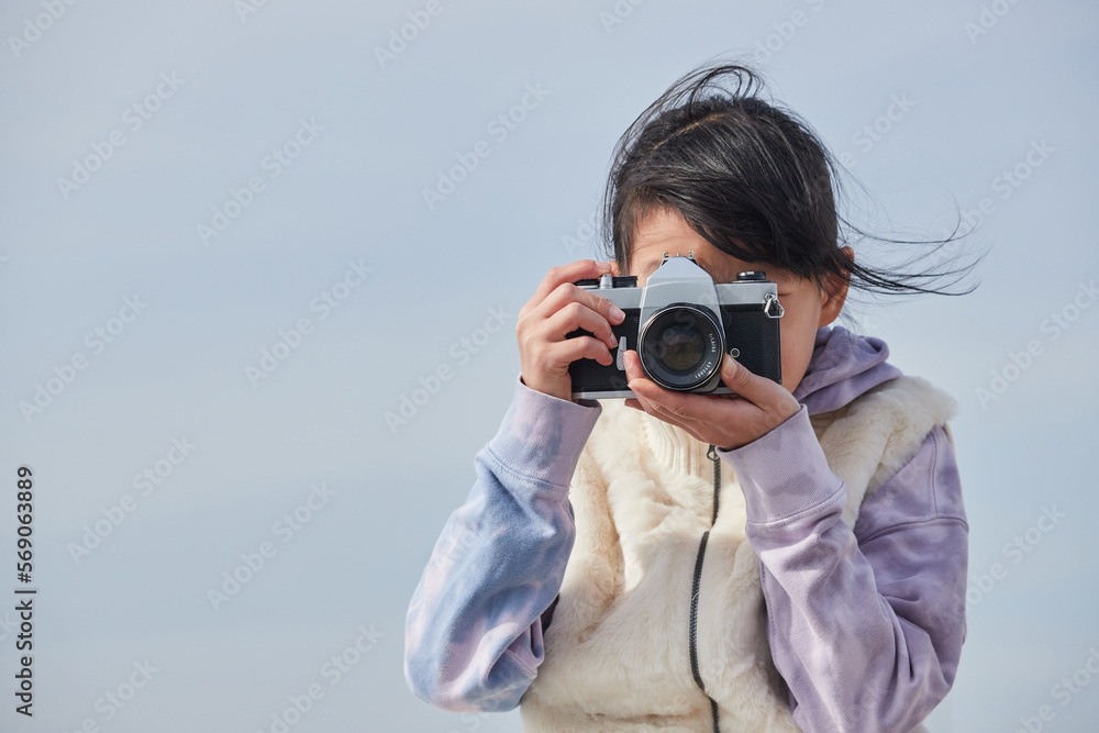 冬の屋外で古いフィルムカメラを遊んでいる小学生の女の子の様子 冬の屋外で古いフィルムカメラを遊んでいる小学生の女の子の様子