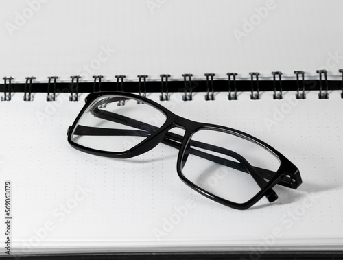 Blank note book, eye glasses closeup. Business accessories concept.