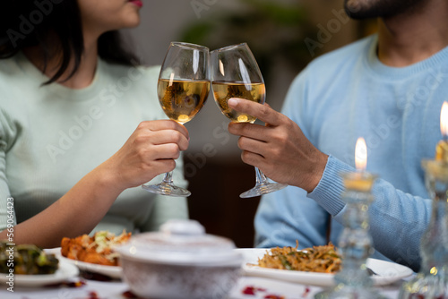 closeup shot of couple champagnes wine glass during wedding anniversary or valentines celebration at candle light dinner - concept of romantic lights, dating and engaged.