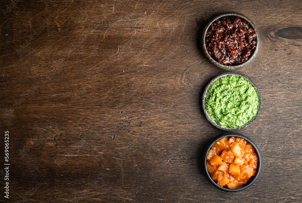 Set of indian chutneys in bowls on wooden background, top view, copy space Set of indian chutneys in bowls on wooden background, top view, copy space