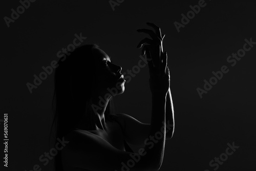 Dark female silhouette, hands and face. Artistic portrait. Required photo of the woman's body. Black and white silhouette of female body art photography.