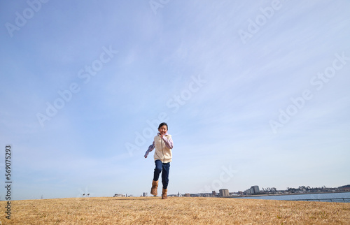 冬の海岸の公園で元気で跳んで遊ぶ小学生の女の子の様子