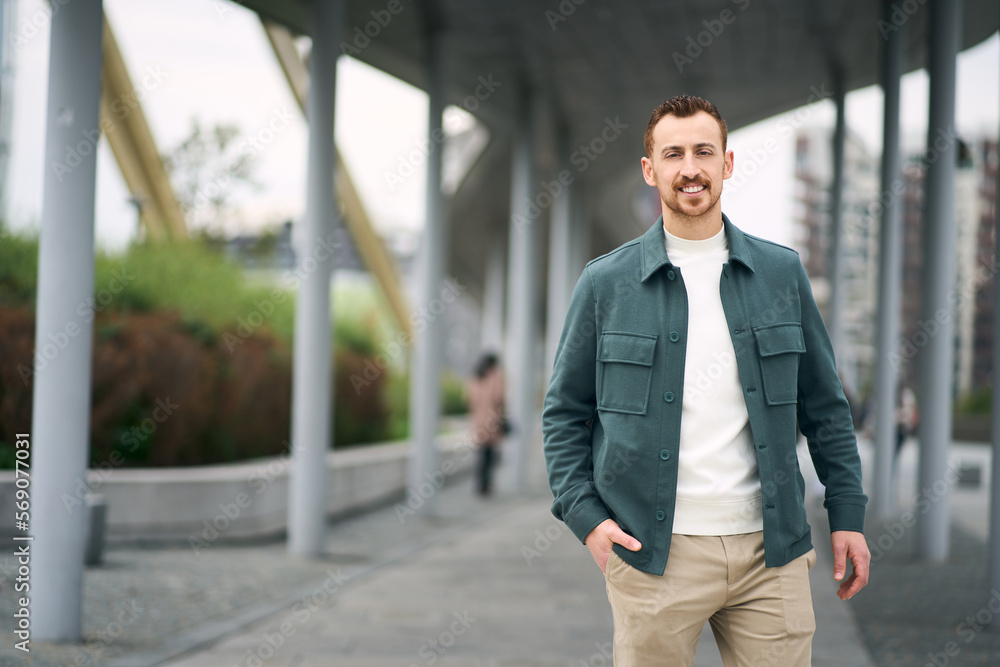 Happy tourist man looking at camera and walking at street, copy space. Smiling guy enjoying positive lifestyle outdoors. Vacation, travel concept Happy tourist man looking at camera and walking at street, copy space. Smiling guy enjoying positive lifestyle outdoors. Vacation, travel concept