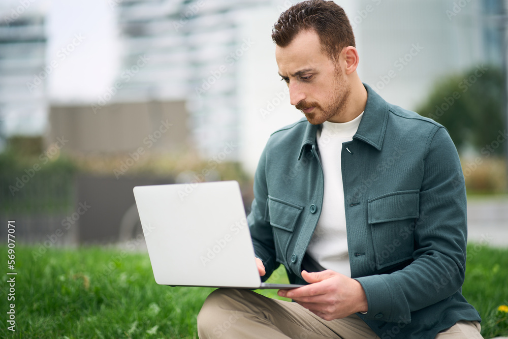 University student studying online using laptop while sitting in campus alone University student studying online using laptop while sitting in campus alone