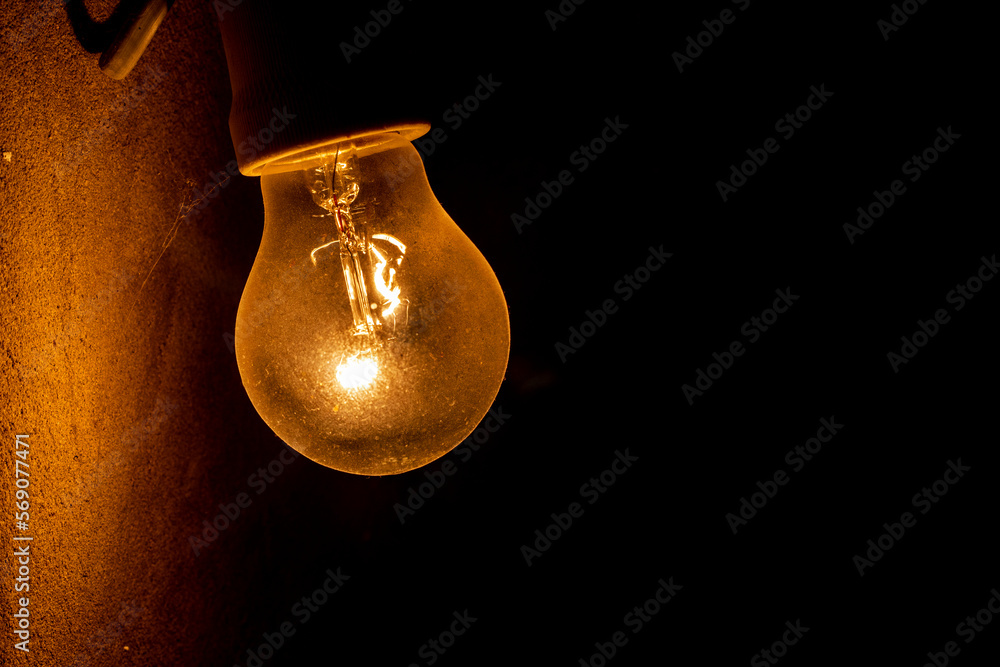 weakly burning electric light bulb in the dark near the wall. blackout, energy saving, bomb shelter.. weakly burning electric light bulb in the dark near the wall. blackout, energy saving, bomb shelter..