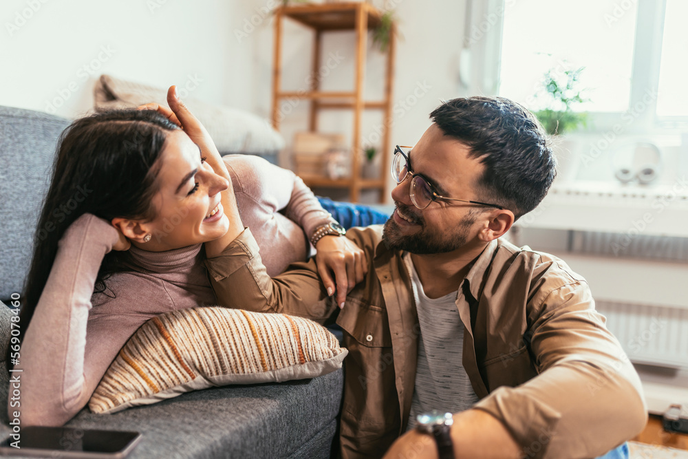 Happy young Caucasian couple relax on cozy sofa at home hugging Happy young Caucasian couple relax on cozy sofa at home hugging
