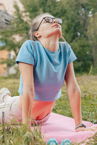 Natural beaty athletic woman relaxing stretching after abs exercises on mat. Fitness Muscular shaped abdominal girl stretching at yoga  training retreat. Wearing sportswear plain mock up shirt..