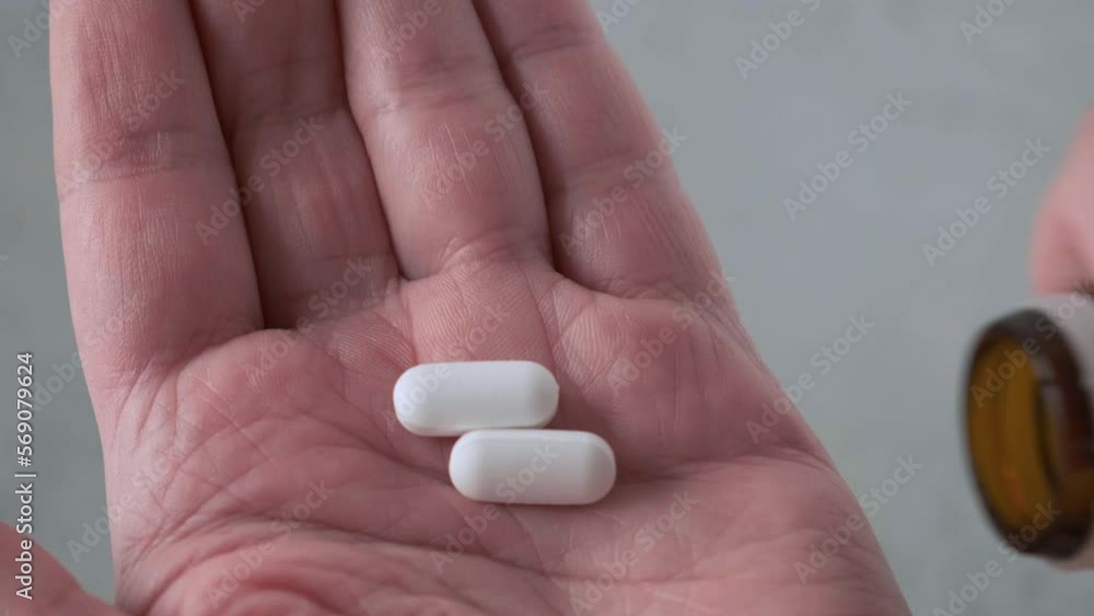 Man taking painkiller or analgetic pills on male hand pouring tablets from meds bottle. Taking medicine, health care, pharmacy and treatment concept. Close up Man taking painkiller or analgetic pills on male hand pouring tablets from meds bottle. Taking medicine, health care, pharmacy and treatment concept. Close up