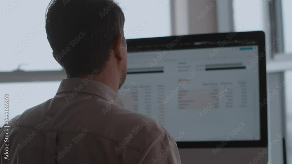 Man in office, sitting in front of a computer and analyzing stock rates. White color worker working with diagrams on the screen. Man in office, sitting in front of a computer and analyzing stock rates. White color worker working with diagrams on the screen.