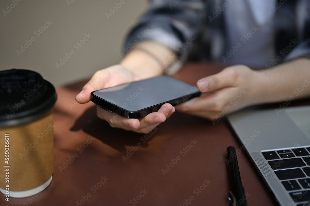 Close-up image of an Asian woman remote working at the coffee shop, using her smartphone. Close-up image of an Asian woman remote working at the coffee shop, using her smartphone.