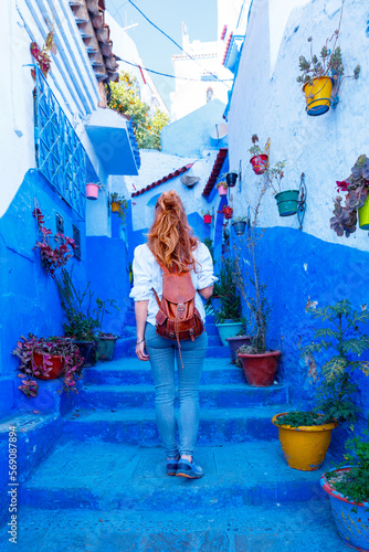 Woman walking in Chefchaouen typical blue street in Morocco © M.studio