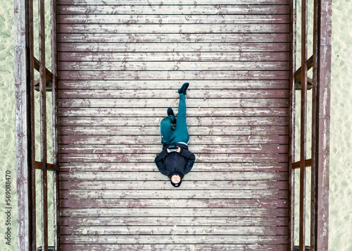 Obraz na płótnie Aerial view landscape. A person lying on a wooden footbridge. Photo from a drone. w salonie