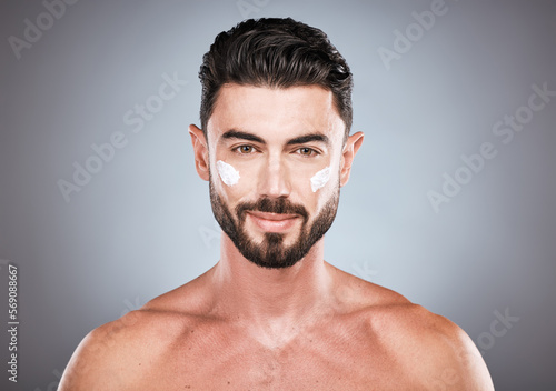 Face portrait, skincare cream and man in studio isolated on a gray background for wellness. Cosmetics, dermatology and young male model with lotion, creme or moisturizer product for facial health.