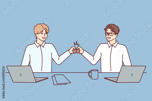 Two man managers bang their fists celebrating successful completion of deal. Guys in white shirts stand near table with laptops saying goodbye after finishing work