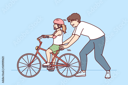 Loving father helps pre-teenage daughter learn to ride bike. Happy childhood for little girl in helmet learning to ride bicycle under supervision of caring dad or brother