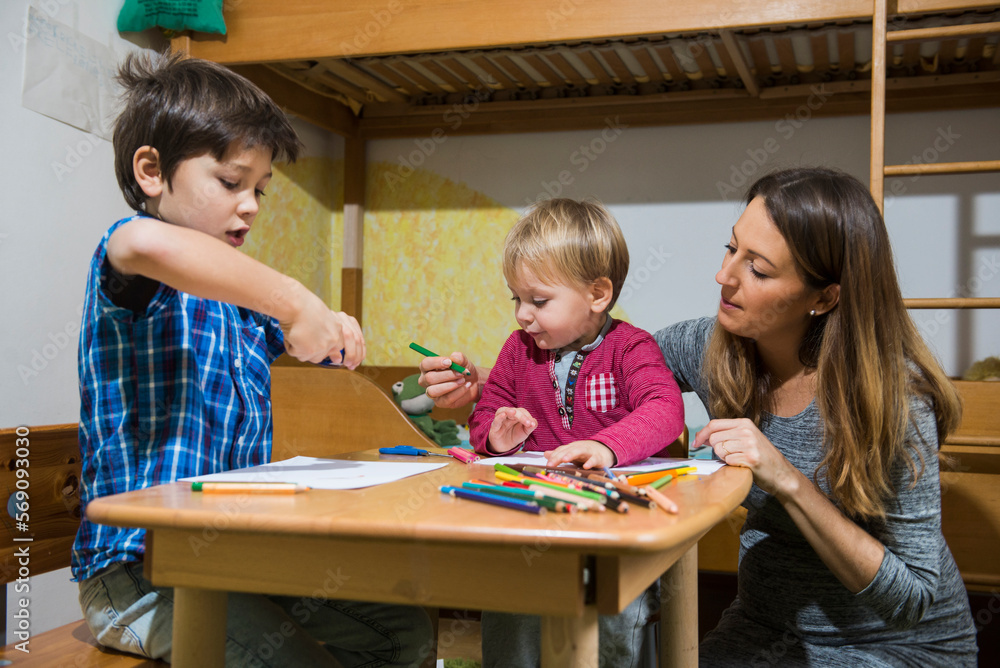 Brothers enjoying with coloured pencils while mother is assisting them, Munich, Germany Brothers enjoying with coloured pencils while mother is assisting them, Munich, Germany