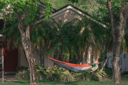 Male college student checks phone in front yard hammock photo