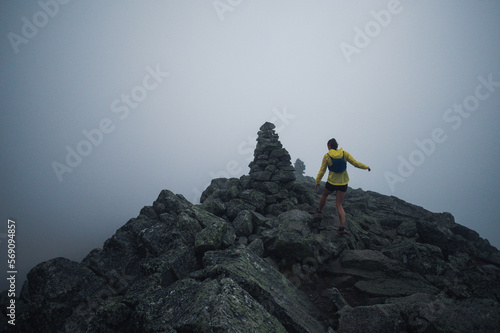 Woman running ridge in early morning fog photo