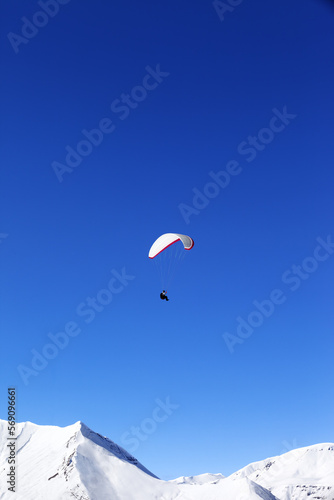 Paraglider in snowy winter mountains at sun day