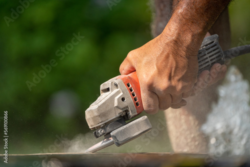 Worker using an angle grinder sanding and grinding concrete surface outdoor