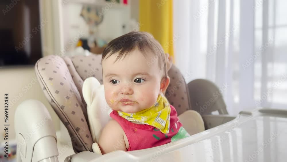 baby eats dirty. mom feeds with a spoon in the table for feeding baby daughter. dirty baby messy kid eats from a spoon indoors. kindergarten kids dream lifestyle concept baby eats dirty. mom feeds with a spoon in the table for feeding baby daughter. dirty baby messy kid eats from a spoon indoors. kindergarten kids dream lifestyle concept