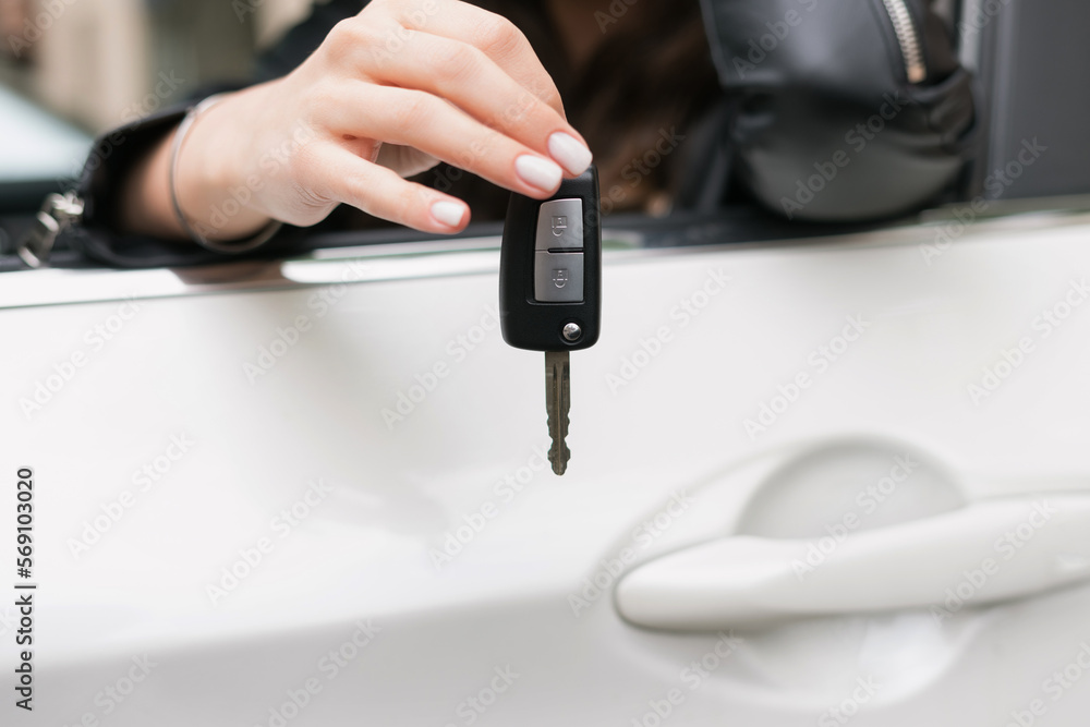 Close-up of a woman's hand holding the car key. Buying a new car. Focus on key