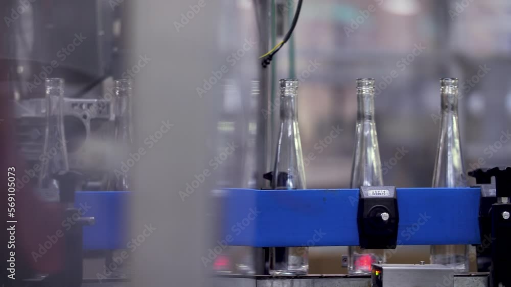 Empty slender wine bottles carried by an automated conveyor belt from one part to another of a winery. Static closeup shot.
Empty slender wine bottles carried by an automated conveyor belt from one part to another of a winery. Static closeup shot.