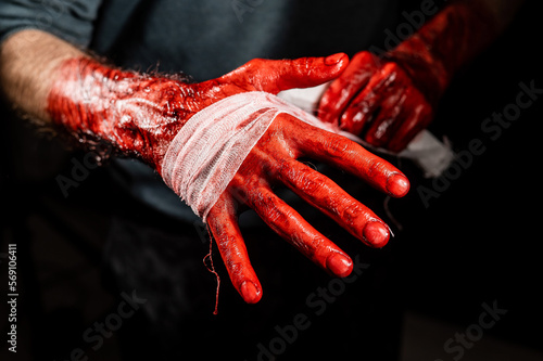 Canvastavla A man covered in blood bandages his hands.
