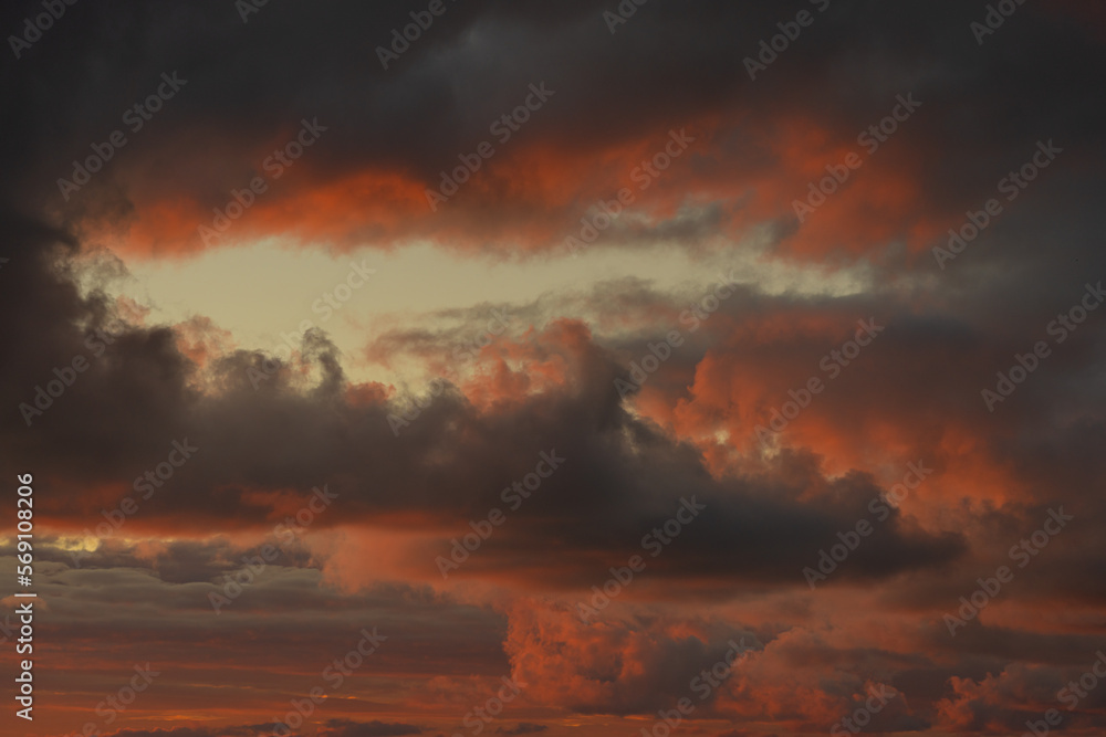 Sunset sky. Frightening dark clouds are illuminated by the red-orange light of the sun. Beautiful sky. Natural background.