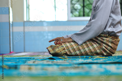 A Muslim male person wearing attractive apparel are praying in mosque photo