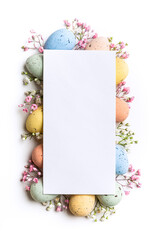 Easter composition of Easter quail eggs, flowers, paper blank over white background. Spring holidays concept with copy space. Overhead shot