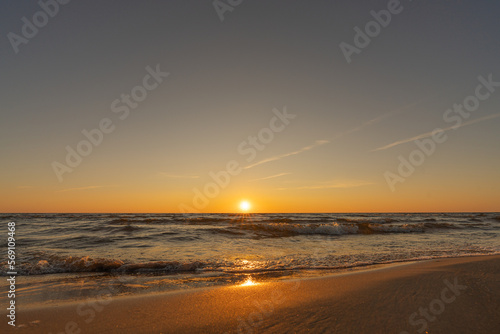 Sunset in a cloudless sky on the coast of the Gulf of Finland in Ust-Narva. The sky is clear, the waves gently roll on the sand. Estonia, Narva-Jyesuu. Natural background. Space for text.