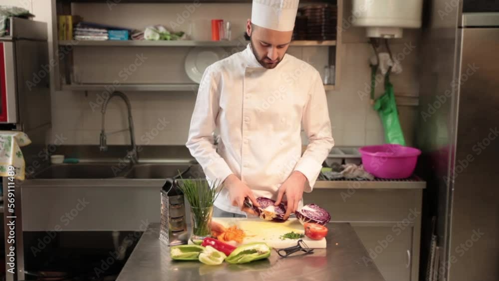 Lockdown shot of chef chopping cabbage on cutting board in commercial kitchen Lockdown shot of chef chopping cabbage on cutting board in commercial kitchen