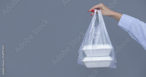 Woman s hands holding PVC plastic bag with takeaway foam lunch boxes. Single use food containers  donation concept.