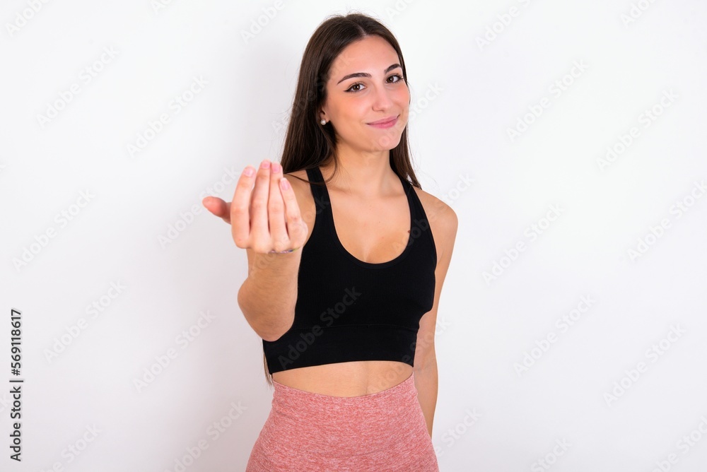 young woman wearing sportswear over white studio background, inviting you to come, confident and smiling making a gesture with hand, being positive and friendly. young woman wearing sportswear over white studio background, inviting you to come, confident and smiling making a gesture with hand, being positive and friendly.