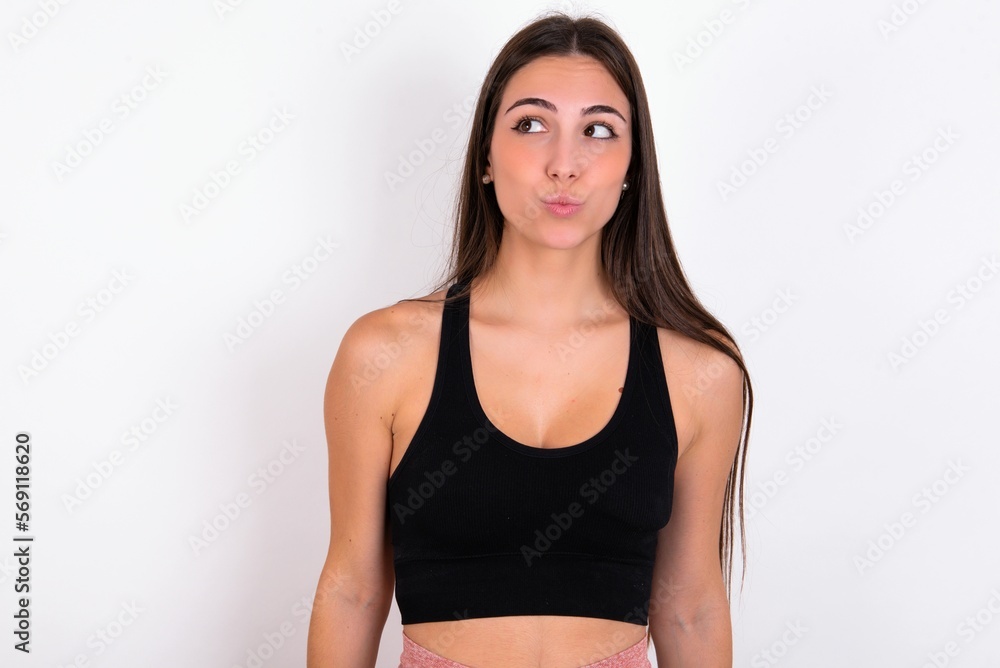 young woman wearing sportswear over white studio background, looks pensively aside, plans actions after university, imagines what to do Thinks over about new project. young woman wearing sportswear over white studio background, looks pensively aside, plans actions after university, imagines what to do Thinks over about new project.