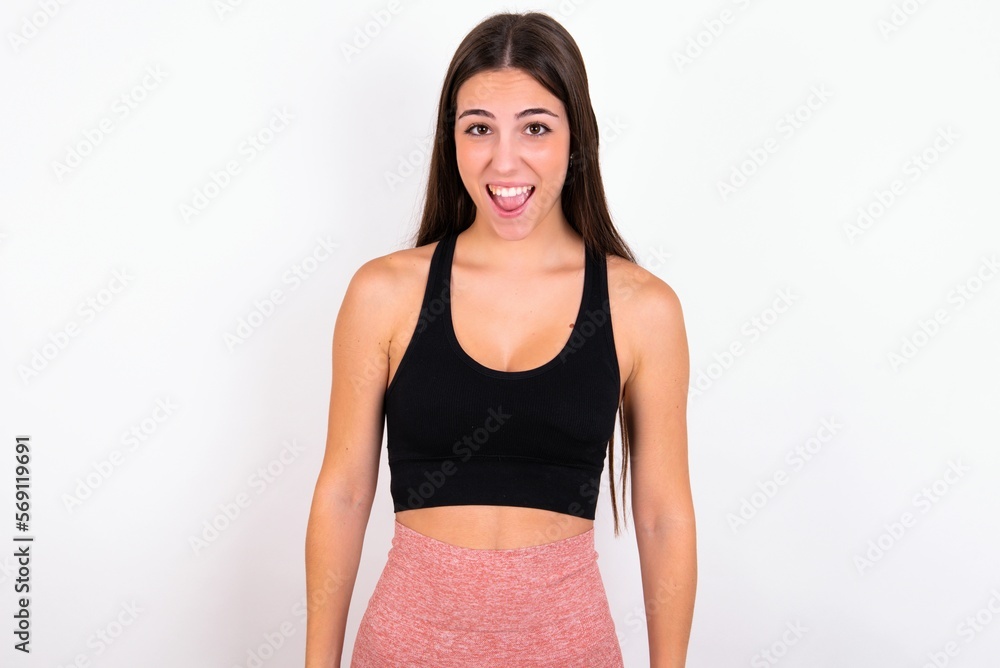 Emotional attractive young woman wearing sportswear over white studio background with opened mouth expresses great surprise and fright, stares at camera. Unexpected shocking news and human reaction. Emotional attractive young woman wearing sportswear over white studio background with opened mouth expresses great surprise and fright, stares at camera. Unexpected shocking news and human reaction.