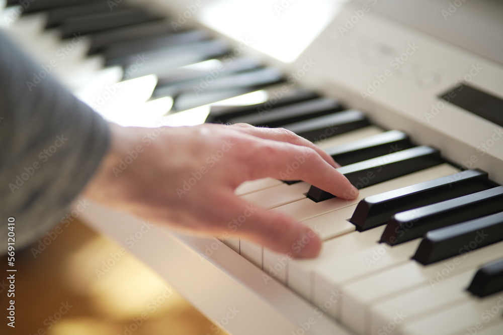 Fototapeta premium A man's hand expertly playing a white grand piano. The focus and attention to detail in this image capture the essence of musical talent and passion. Ideal for use in music-related projects.