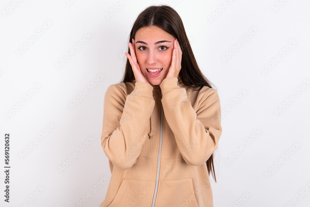 young woman wearing beige sweater over white studio background Pleasant looking cheerful, Happy reaction young woman wearing beige sweater over white studio background Pleasant looking cheerful, Happy reaction