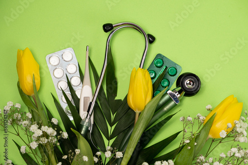 Bouquet of flowers and stethoscope on a green background, happy doctors day, nurses week and other medical holidays. photo