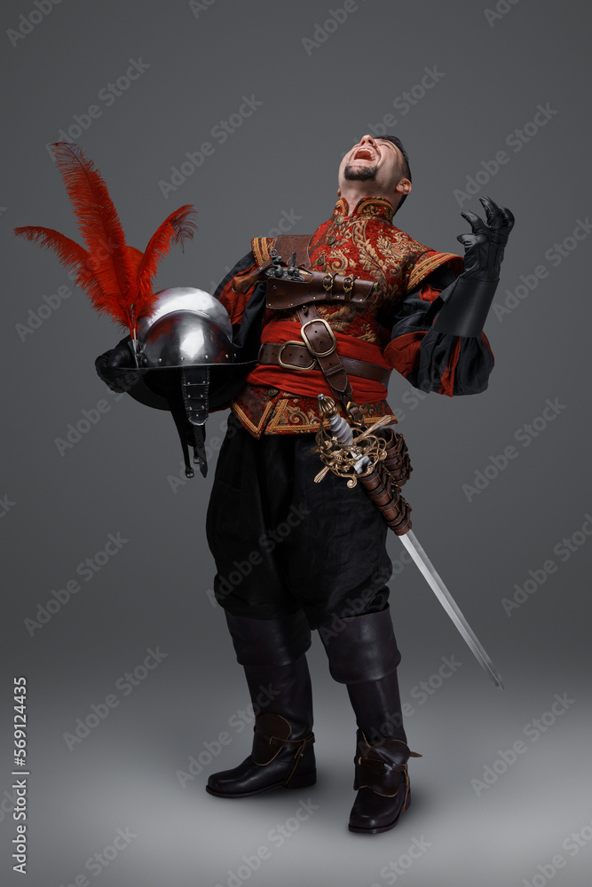 Obraz premium Shot of angry conquistador knight with epee holding plumed helmet.
