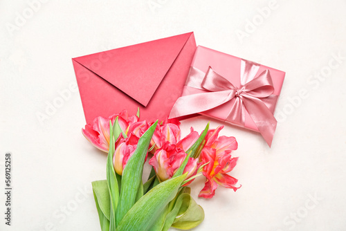 Beautiful tulip flowers, envelope and gift for Women's Day celebration on white background © Pixel-Shot