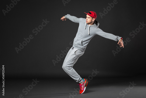 Full body portrait of young dancer dancing on dark gray background. photo