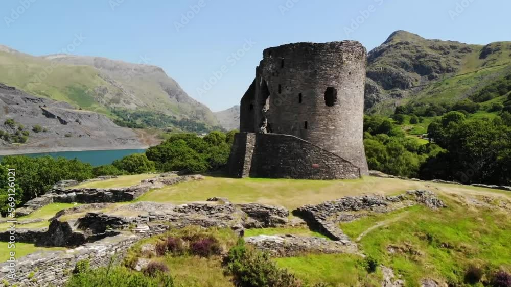 Aerial shot of castle ruins in Wales, shot on a sunny and warm day with the beautiful countryside in the background including a lake, rolling hills, and trees Aerial shot of castle ruins in Wales, shot on a sunny and warm day with the beautiful countryside in the background including a lake, rolling hills, and trees