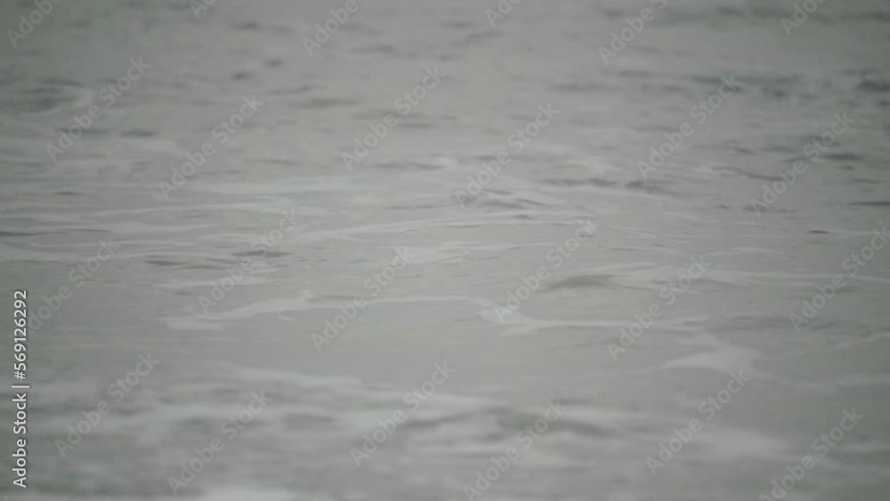 Closeup, ocean tide crashing onto beach shore on a gloomy overcast day Closeup, ocean tide crashing onto beach shore on a gloomy overcast day