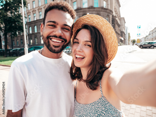 Smiling beautiful woman and her handsome boyfriend. Woman in casual summer clothes. Happy cheerful family. Female having fun. Sexy couple posing in the street at sunny day. In hat. Taking selfie