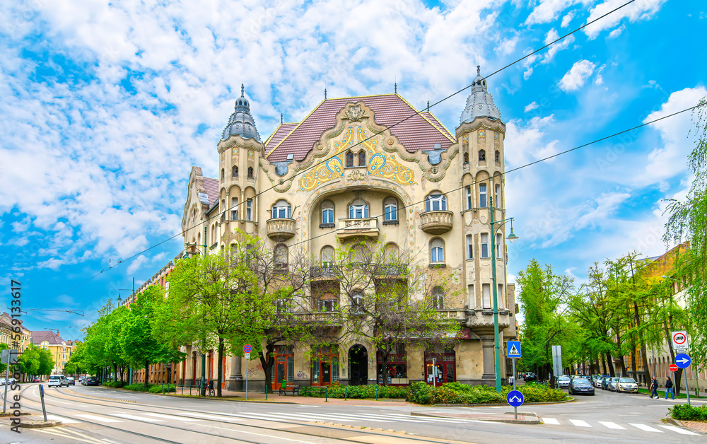 Fototapeta premium Front view the facade of beautiful old building with old sculptures in the city center of Szeged, Hungary 