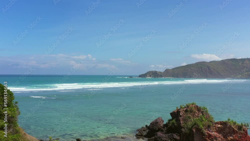 Aerial Beautiful View Of Wavy Seascape At Beach, Drone Flying Forward By Mountain On Sunny Day - Lombok, Indonesia Aerial Beautiful View Of Wavy Seascape At Beach, Drone Flying Forward By Mountain On Sunny Day - Lombok, Indonesia