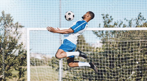 Sports, soccer and man jump with ball playing game, training and exercise on outdoor field. Fitness, workout and male football player for defence, goalkeeper and in action for goals in competition