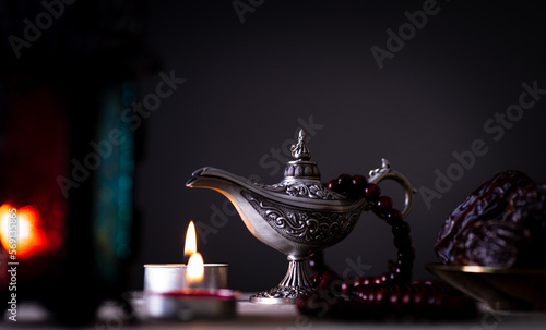 Ramadan food and drinks concept.  Ramadan Lantern with arabian lamp, wood rosary, tea, dates fruit and lighting on a wooden table with dark background.